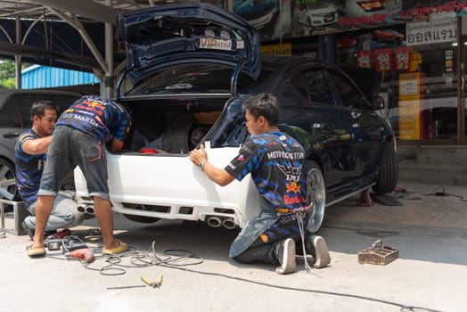 Bangkok, Thailand - April 4, 2024 : Unidentified denter or car mechanic serviceman check and fix body work and fiber bumper body part for fix and repair problem at car garage or repair shop