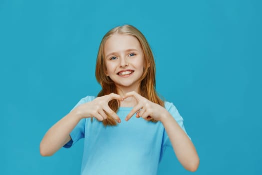 Happy child in a blue shirt forming a heart with her hands, set against a vibrant blue background, symbolizing affection and well being Ideal for health, family, and happiness concepts