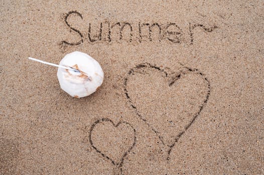 inscription Summer and two hand-drawn hearts in sand on a sandy beach with coconut the sea. Concept of summer vacation and love at resort