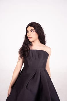 Beautiful woman with curly black hair while wearing a black dress inside the white room