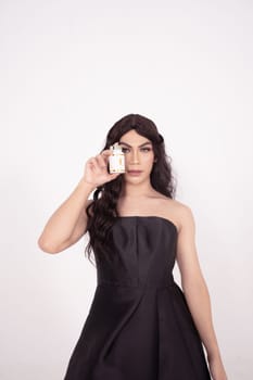 Asian woman poses with skincare in her hands while wearing a black wedding dress inside the studio