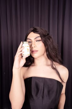 Beautiful Woman holding skincare in her hand while wearing a black dress with black hair in front of the black curtain