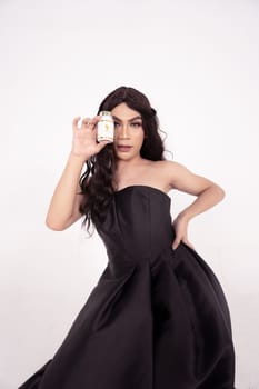 glamor woman holding a skincare jar in her hands with black hair and dress inside the white room