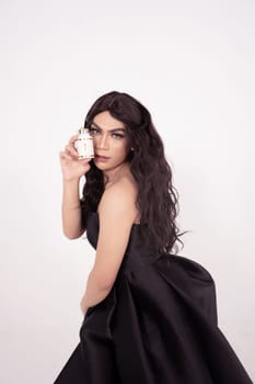 Asian woman poses with skincare in her hands while wearing a black wedding dress inside the studio