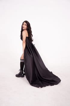 Asian woman in a black bride dress with a tail pose in a white room inside the studio