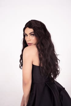 Beautiful woman with curly black hair while wearing a black dress inside the white room