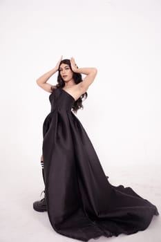 Asian woman in a black bride dress with a tail pose in a white room inside the studio