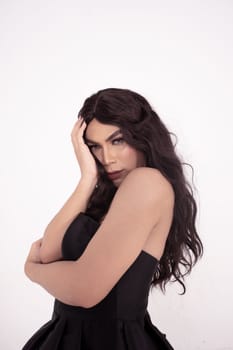 Asian woman sadly holding her face with her hand while wearing a black dress with brown hair