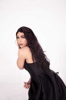 Beautiful Asian woman with dark brown hair posed in a black dress inside the white studio