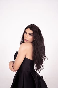 Beautiful Asian woman with dark brown hair posed in a black dress inside the white studio