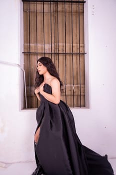 Sad Asian woman standing in front of the brown wooden window while wearing a black dress inside the studio