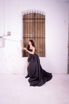 Sad Asian woman standing in front of the brown wooden window while wearing a black dress inside the studio