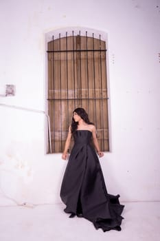 Elegance woman in a black dress standing in front of the rustic wooden window in a white studio