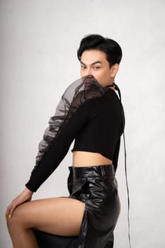 Beautiful Asian man wearing a black tank top with a happy face while in front of the white background