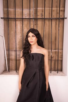Elegance woman in a black dress standing in front of the rustic wooden window in a white studio