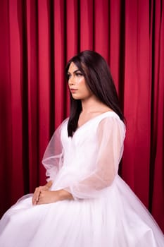 Beautiful Asian woman in white bride dress with black hair in front of the red curtain