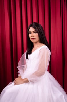 Beautiful Asian woman in white bride dress with black hair in front of the red curtain