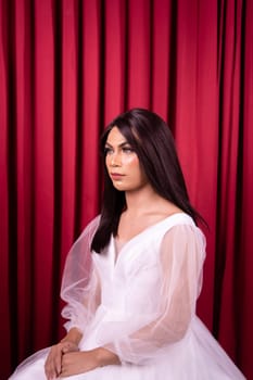 Beautiful Asian woman in white bride dress with black hair in front of the red curtain