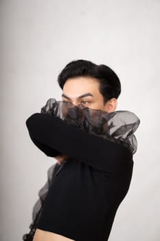 Asian man with a pretty face wearing a black costume while posing inside the white room at the studio
