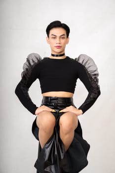 The beautiful man sitting on the chair while wearing a black costume with a pretty face inside the white studio