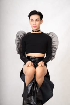 The beautiful man sitting on the chair while wearing a black costume with a pretty face inside the white studio