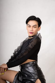Asian man with a pretty face wearing a black costume while posing inside the white room at the studio