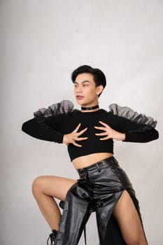 Asian man with a pretty face wearing a black costume while posing inside the white room at the studio
