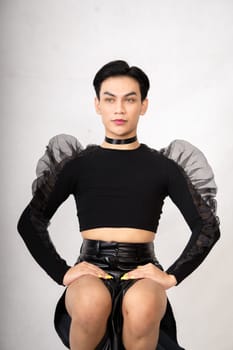 The beautiful man sitting on the chair while wearing a black costume with a pretty face inside the white studio