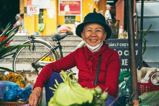 Old Vietnamese woman selling fruits at an Asian food market in Hoi An in Vietnam. Hoi An, Vietnam - December 1, 2024