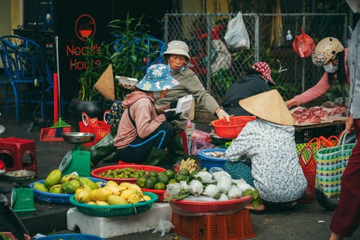 Vietnamese women sellers at Asian street food market in old town in Hoi An in Vietnam in Asia. Hoi An, Vietnam - December 2, 2024