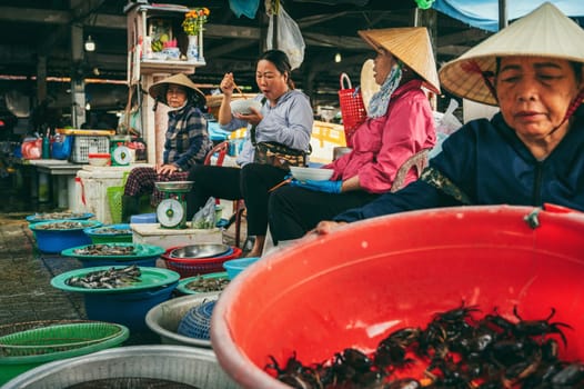 Vietnamese women seafood vendors at Asian street fish market in Hoi An in Vietnam. Hoi An, Vietnam - December 2, 2024