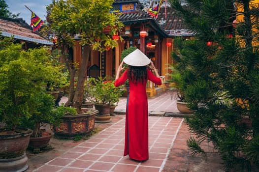 Back of a woman tourist traveler in a Vietnamese cone hat at the Buddhist temple in Hoi An in Vietnam in Asia