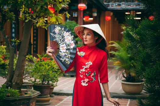 Portrait of a young woman tourist traveler in a Vietnamese cone hat Non La at the Hoi An pagoda in Vietnam in Asia