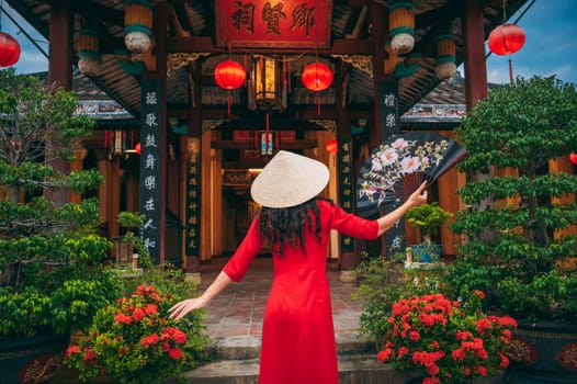 Back of a female tourist traveler in a Vietnamese cone hat Non La at the Buddhist temple in Vietnam in Asia