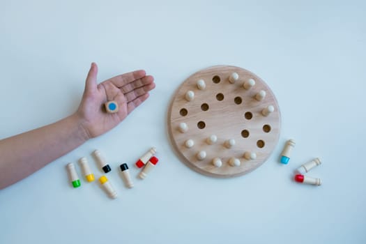 Wooden memory game for child with colorful pegs on white background.