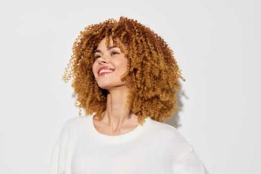 a happy woman with voluminous curly hair, showing a warm smile She stands against a simple white background, enhancing her natural beauty and exuding confidence and joy in this bright fashion portra