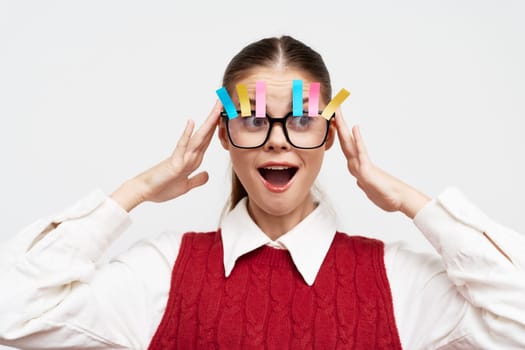 playful girl wearing oversized glasses with colorful clips on her forehead, expressing surprise or excitement, set against a clean white background, emphasizing a lively and whimsical theme