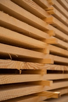 Close side angle of raw timber stack reveals plank alignment, textures, and sawn edges. Strong detail and warm lighting perfect for construction-themed visuals.