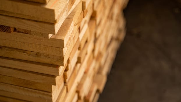Warm-toned wooden planks stacked in depth, slightly blurred toward the rear. The focus and softness create an appealing material or industrial texture image.
