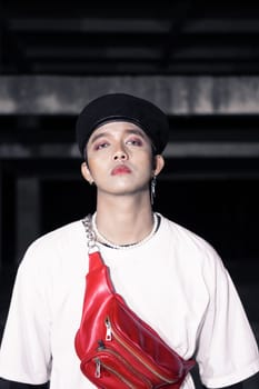 close up shot of an asian man with a red bag while wearing a casual white shirt at night