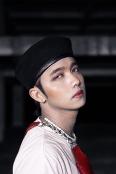 close up shot of an asian man with a red bag while wearing a casual white shirt at night