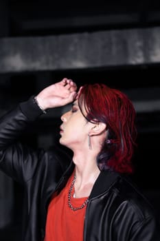 an asian man in a red shirt and black jacket posing with his hands in an abandoned warehouse