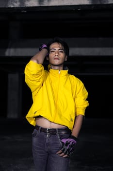 an asian man with a yellow jacket and black hair posing very gallantly in an abandoned building