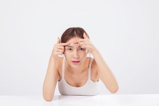 Acne trouble meets careful hands as this teen woman squeezes acne spots, facing blackhead and blemish issues with a clean background and beauty care mindset. isolated studio white background