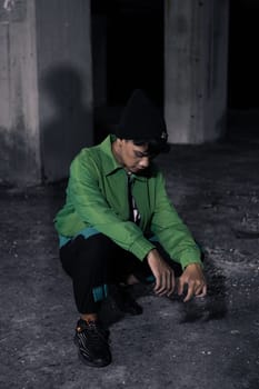an Asian man squats while wearing a green jacket in a haunted building