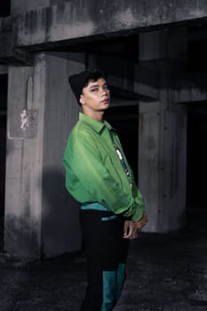 an Asian man smiles while wearing a green parachute jacket and black pants at night