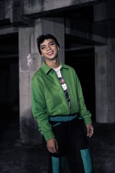 an Asian man smiles while wearing a green parachute jacket and black pants at night