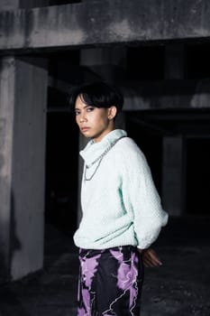 an asian man posing in a white sweater and a chain necklace around his neck in an old building