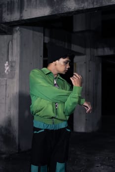 an Asian man smiles while wearing a green parachute jacket and black pants at night
