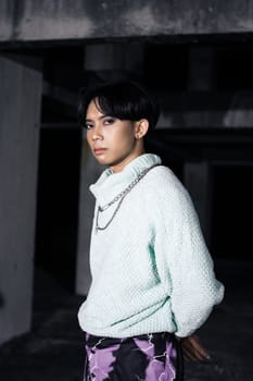 an asian man posing in a white sweater and a chain necklace around his neck in an old building